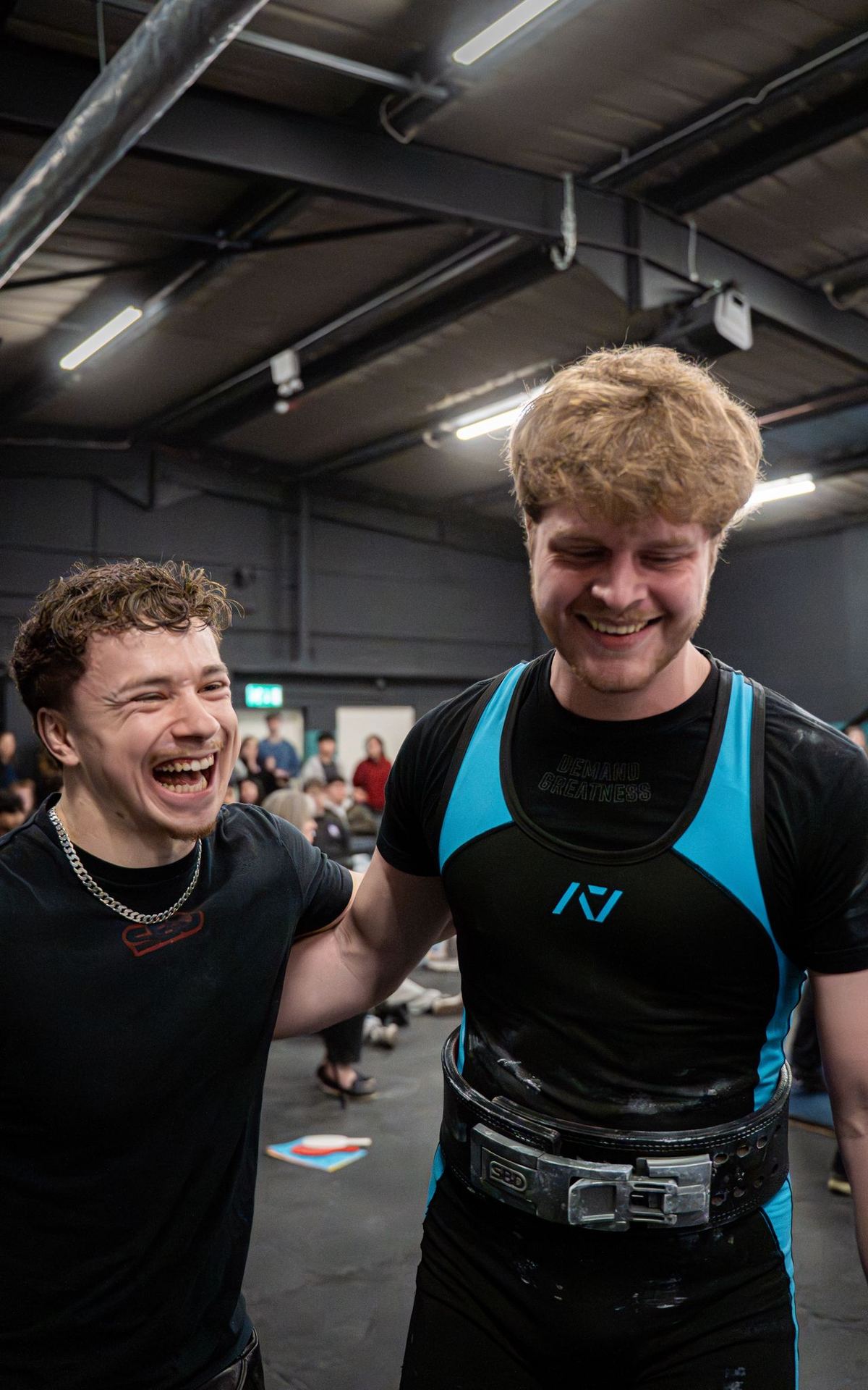 Coach laughing with a lifter in a blue singlet after an attempt