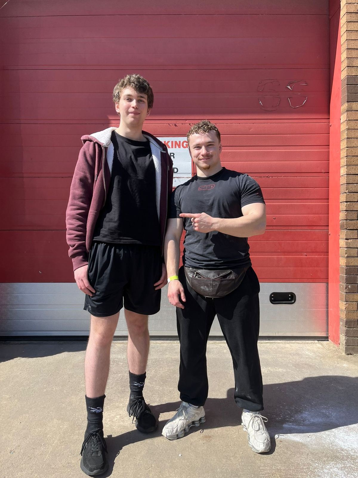 Coach pointing to his lifter in front of a red garage door