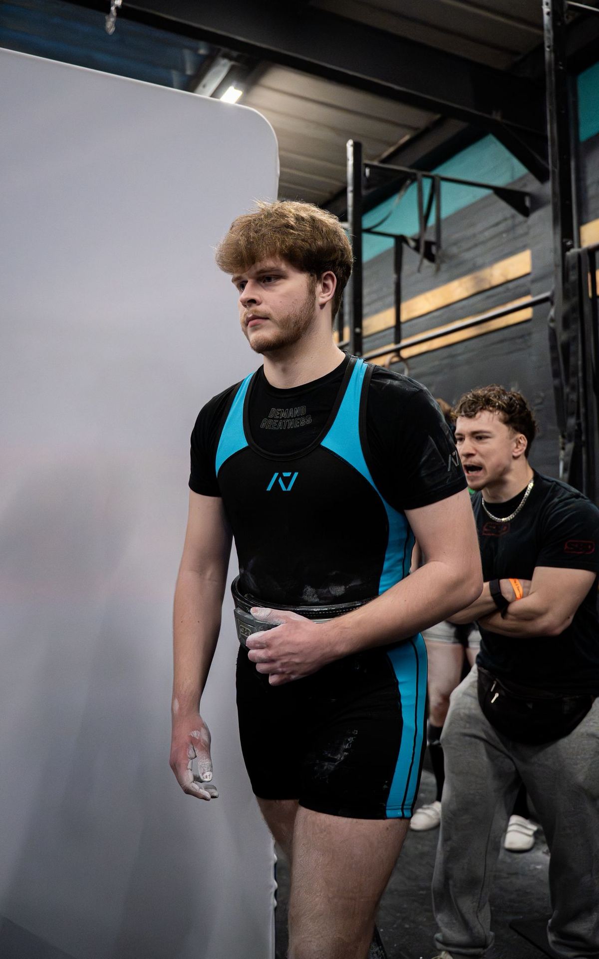 A lifter walks out to the platform while his coach shouts encouragement behind him