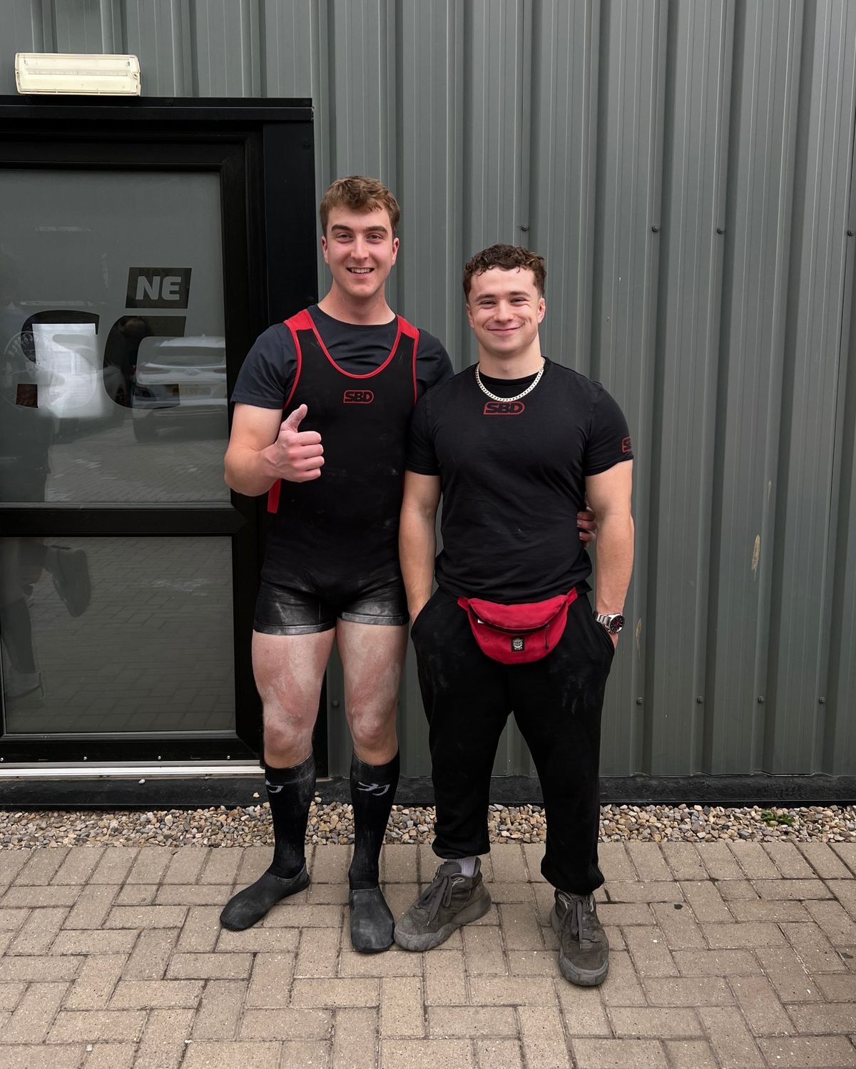 Coach with a lifter giving a thumbs up outside a meet venue