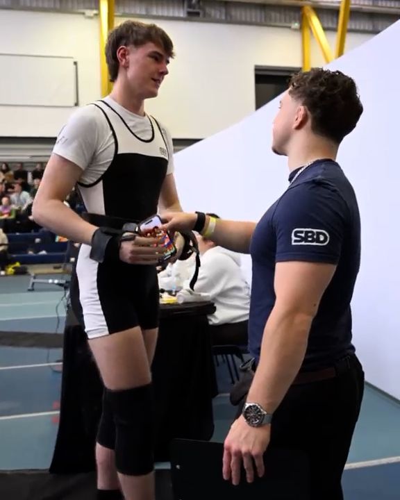 Coach talking with his lifter beside the platform before an attempt